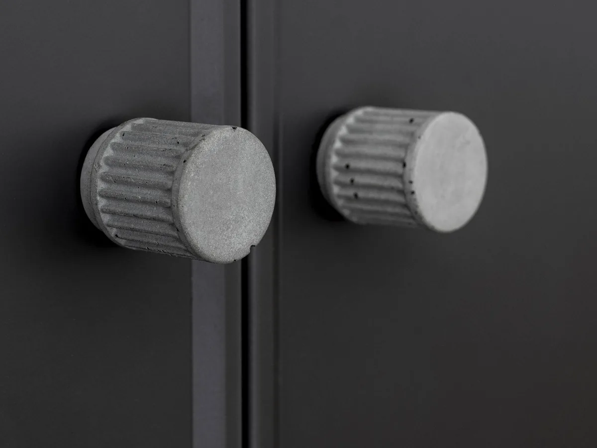 Boutons en béton sur des portes de meuble noires